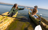 Slideshow: Two university students high five on tule boats.